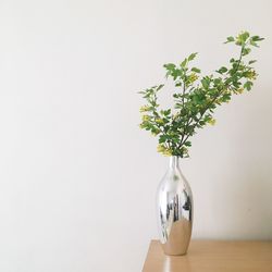 Close-up of vase on table against wall