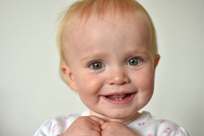 Portrait of cute baby boy smiling against beige background