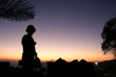 Silhouette man standing against orange sky