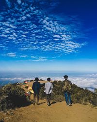 Rear view of people walking on land against cloudscape