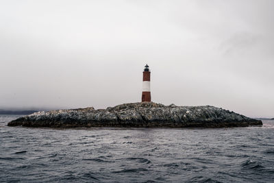 Lighthouse by sea against sky