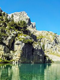 Scenic view of rocks and trees against clear blue sky