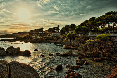 Scenic view of sea by buildings against sky at sunset