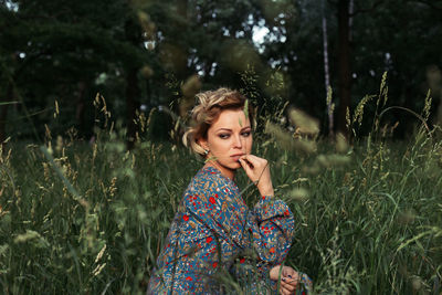 Young woman sitting on field looking away 