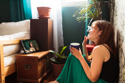 Side view of woman holding sunglasses at home