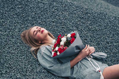 High angle view of woman with bouquet lying on gravels