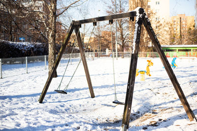 Empty wooden swing in playground. winter scenery, snow