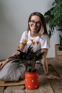 Cheerful woman with potted plants sitting at plant store