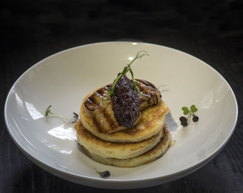 High angle view of pancakes with fried foie gras and onion marmalade on table