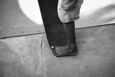 Low section of person child standing on footpath of skateboard