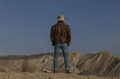 Rear view of adult man legs standing on cliff in tabernas desert, almeria, spain