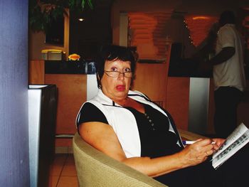 Portrait of woman sitting on chair in restaurant