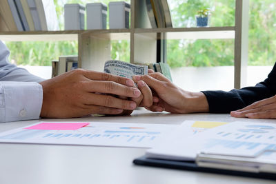 Cropped image of business colleagues dealing in money at office