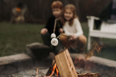 Siblings roasting marshmallows at campfire