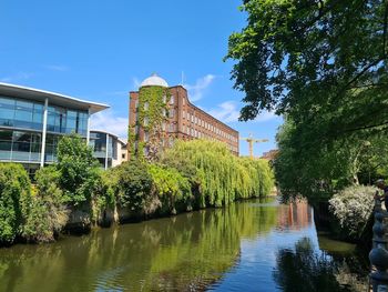 River amidst trees and buildings against sky