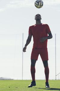 Full length of african american playing soccer on a football pitch