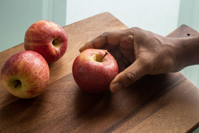 Close-up of hand holding apple on table