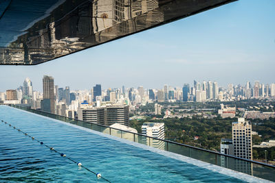 Buildings by swimming pool against sky in city