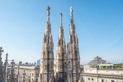 View to spires and statues on roof of duomo through ornate marble fencing. milan, italy