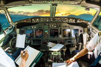 Pilots sitting in cockpit during sunset