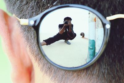 Reflection of man in sunglass photographing through digital camera