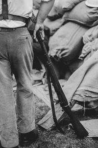 Low section of man with rifle standing outdoors