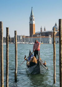 Rear view of men on wooden post in canal