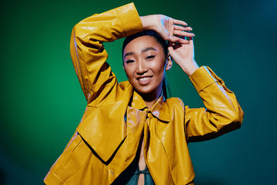 Portrait of woman with arms crossed standing against blue background