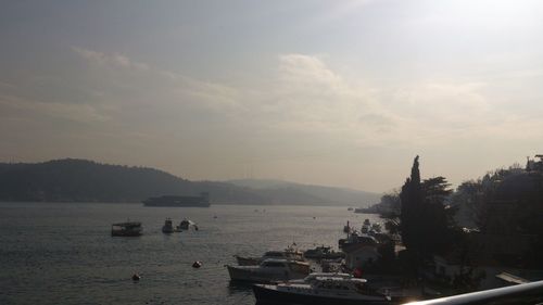 Boats in sea against cloudy sky