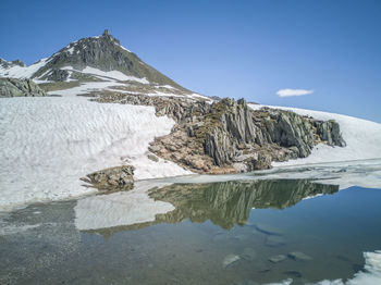 Nufenenpass with a mountain that is reflected in the water of the little lake