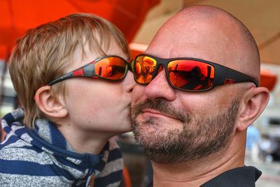 Father and son wear the same glasses. the little boy kisses his father