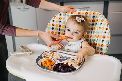 Babys first solid food. solid food for little child 6 months old. cute smiling baby girl in high