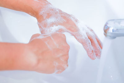 Close-up of hand touching water in bathroom