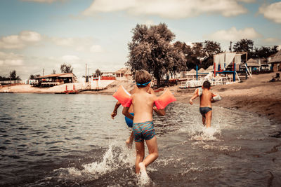 Full length of shirtless boy on beach against sky