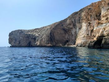 Rock formation in sea against clear sky