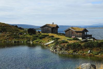 Houses by lake and buildings against sky