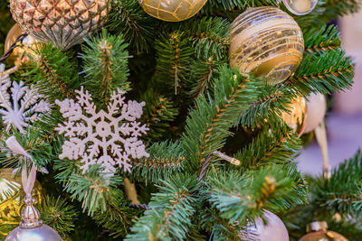 Close up of christmas tree decorated with gold and white balls and snowflake. new year background