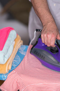 Midsection of man ironing textile on board