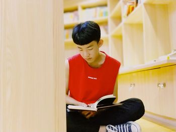 Young woman looking away while sitting on book