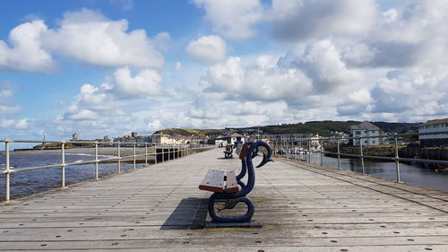 People on pier against sky