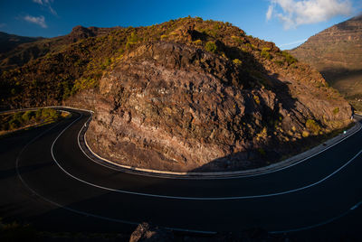 Scenic view of road by mountains against sky