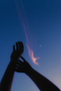 Cropped image of hand against blue sky