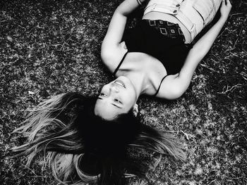 High angle view of smiling young woman lying on grassy field