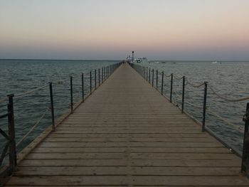 Pier over sea against sky during sunset