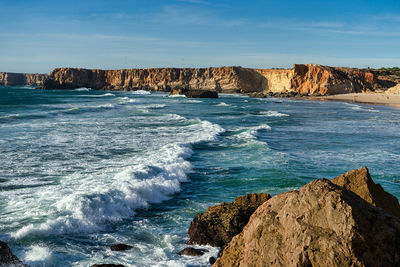 Scenic view of rocks on beach against sky