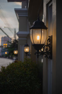 Illuminated lights on house wall at sunset