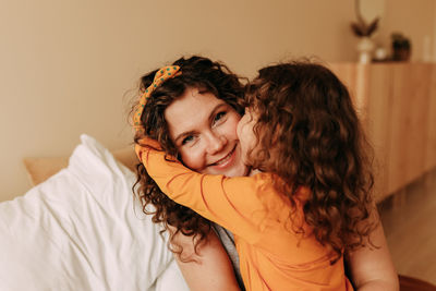 Portrait of happy smiling curly-haired mom and daughter on mother's day at home