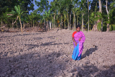 Woman standing by tree in forest