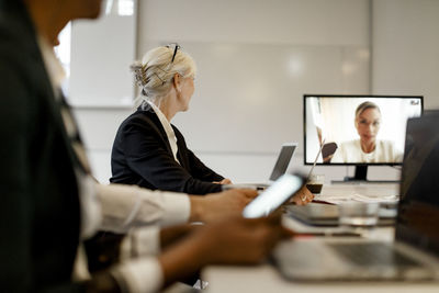 Businesswoman attending video conference with colleagues in meeting at office