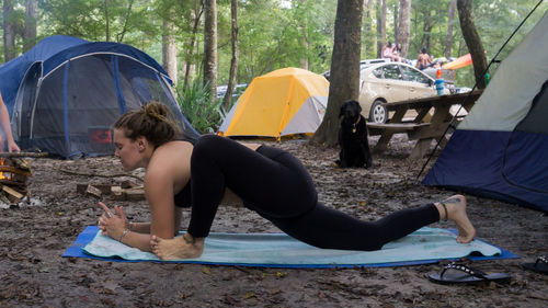 People relaxing on tent in forest